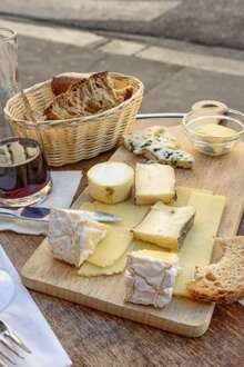 Uma mesa com queijos e copos de vinho, pão e toalhete.